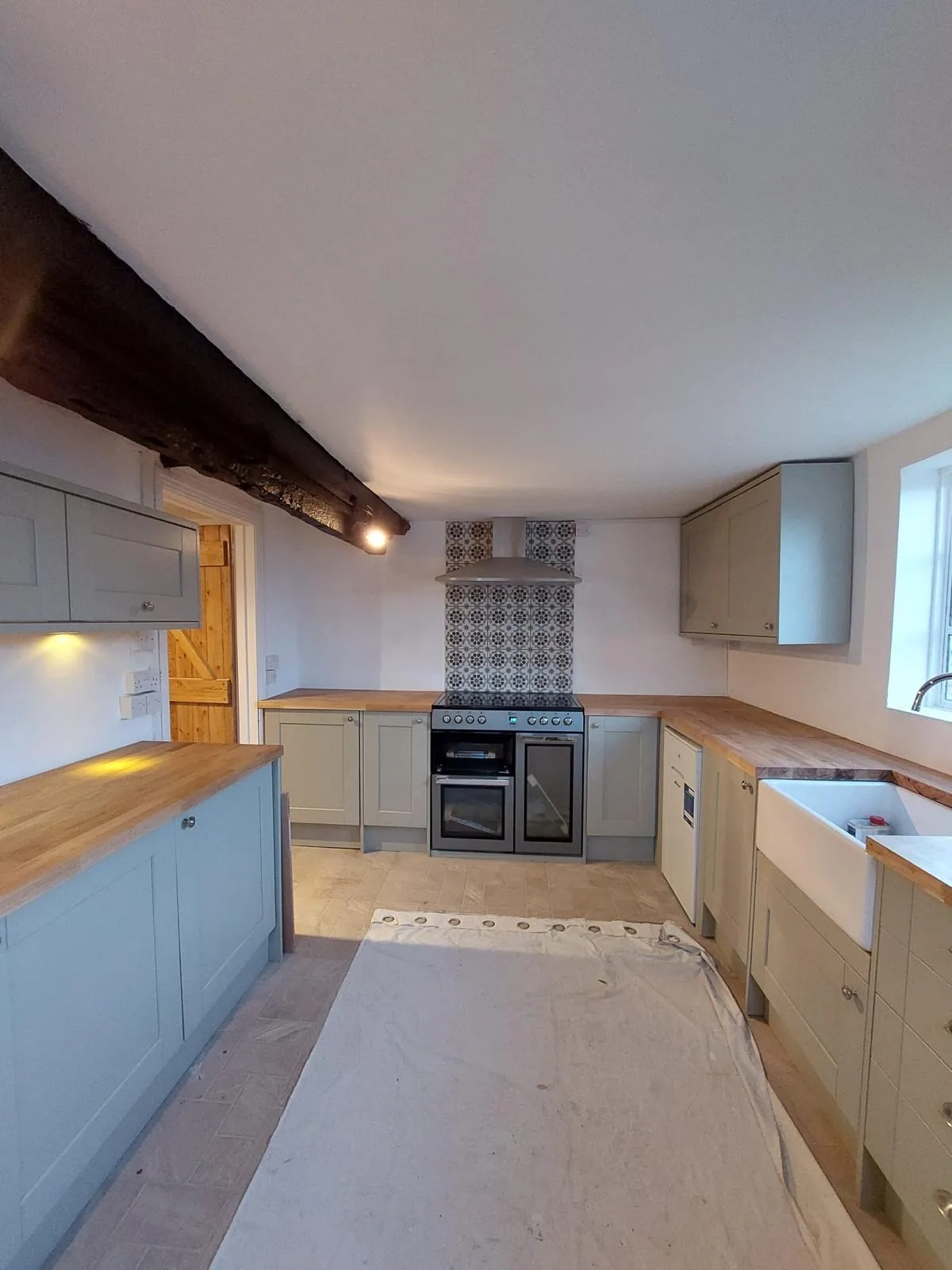 Completed kitchen with range cooker, patterned tile splashback and oak worktops