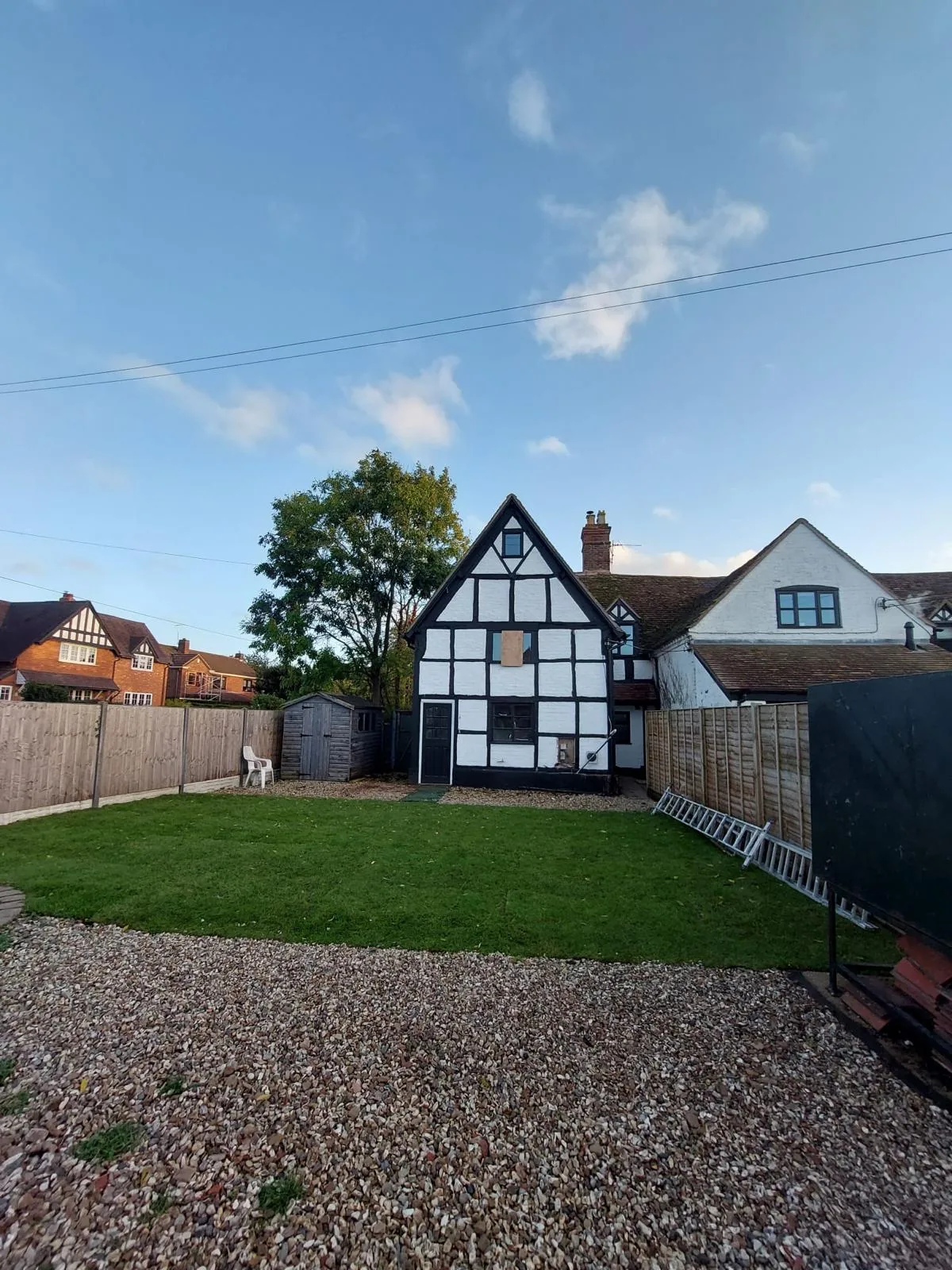 Completed cottage exterior with restored black and white timber framing and new lawn