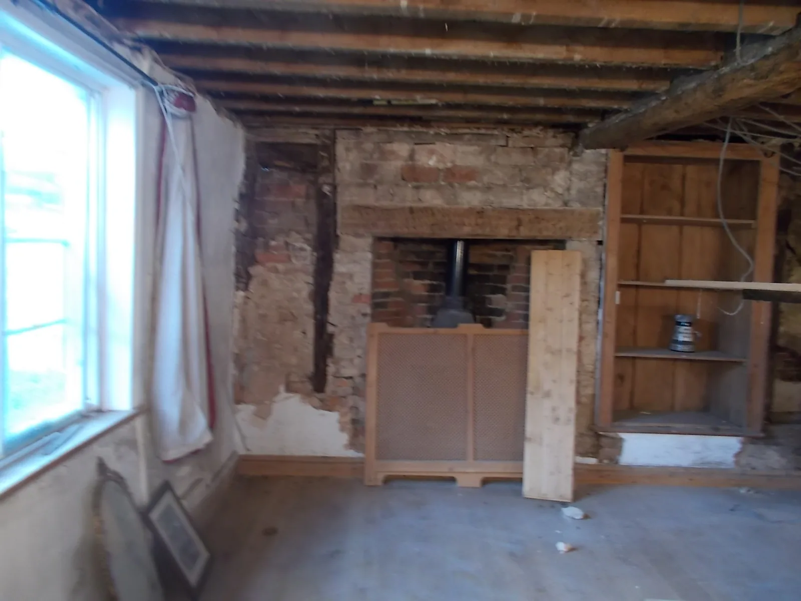 Reception room stripped back to brick, exposing beams and the original fireplace