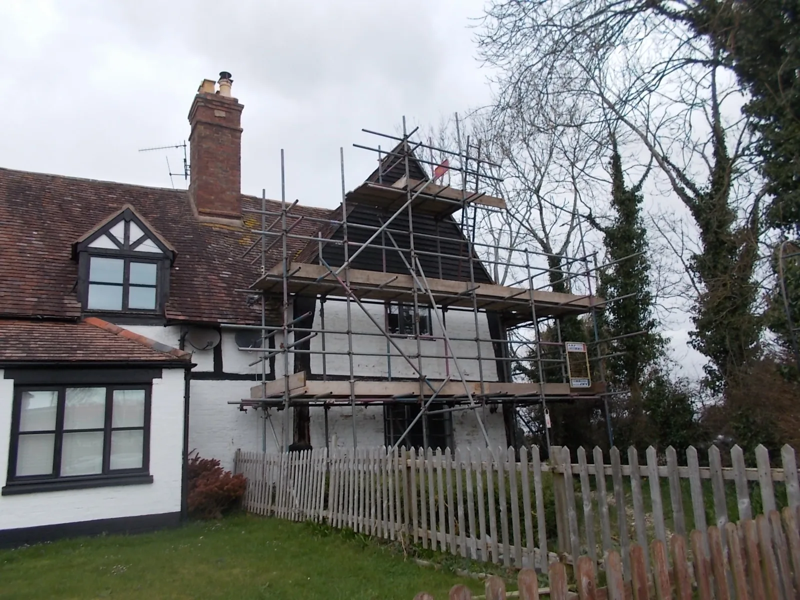 Front elevation of the timber-framed cottage under scaffolding before works