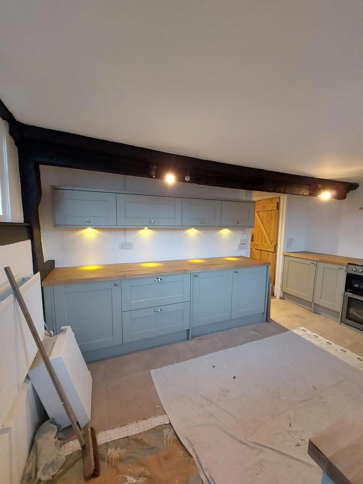 Completed kitchen showing the blue cabinetry run and solid oak door